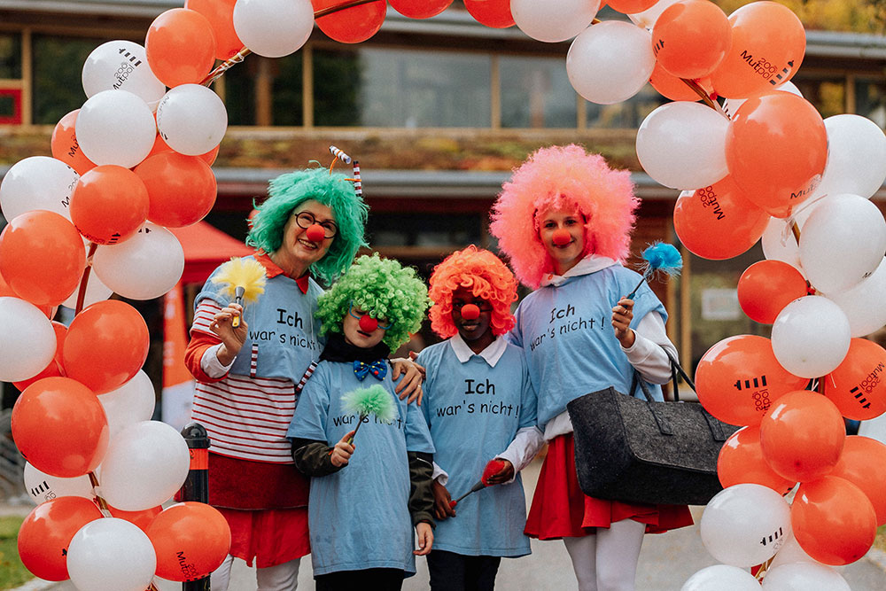 Vier Menschen in Clownkostümen mit bunten Perücken