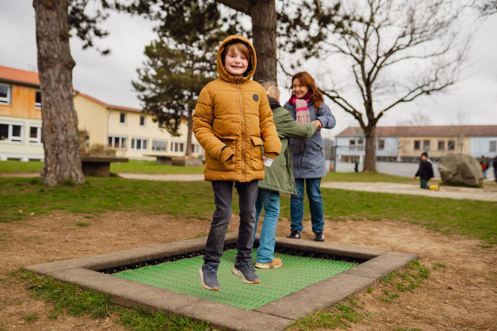 Fröhliches Kind springt auf Spielplatz in Tagesgruppe