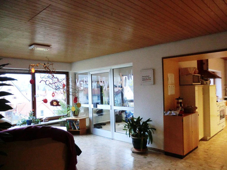 Helle, gemütliche Wohnung mit großen Fenstern, Pflanzen und Dekorationen im Wohnzimmer.