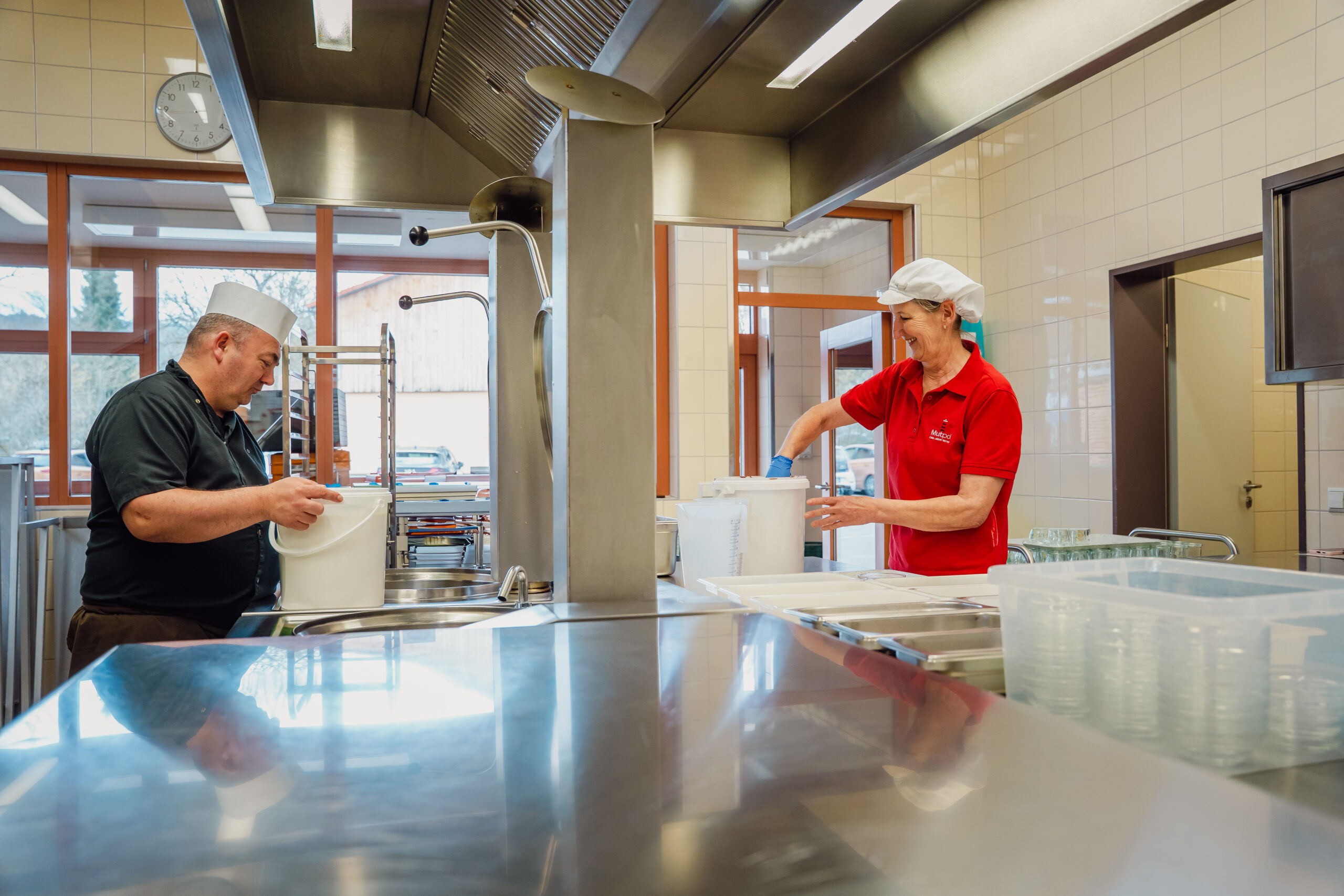 Zwei Küchenmitarbeiter in einem professionellen Küchenumfeld, die Lebensmittel vorbereiten.