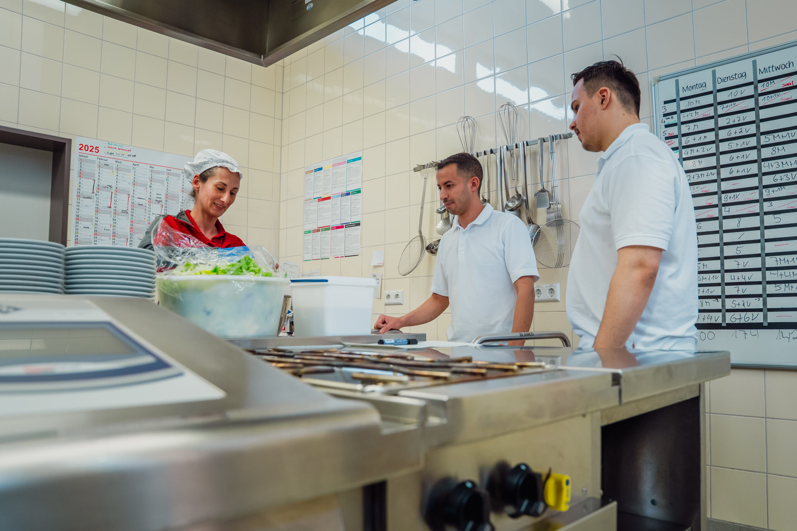 Kochpersonal in einer Küche beim Vorbereiten von Salat.