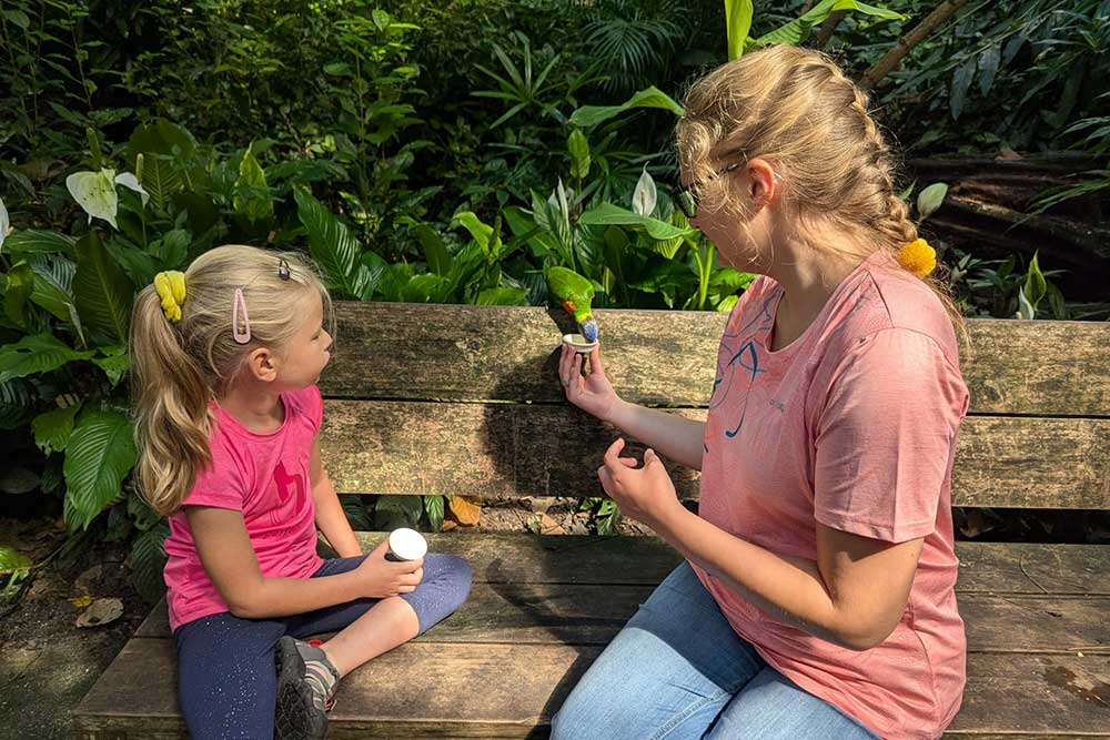 Zwei Mädchen sitzen auf einer Bank im Grünen