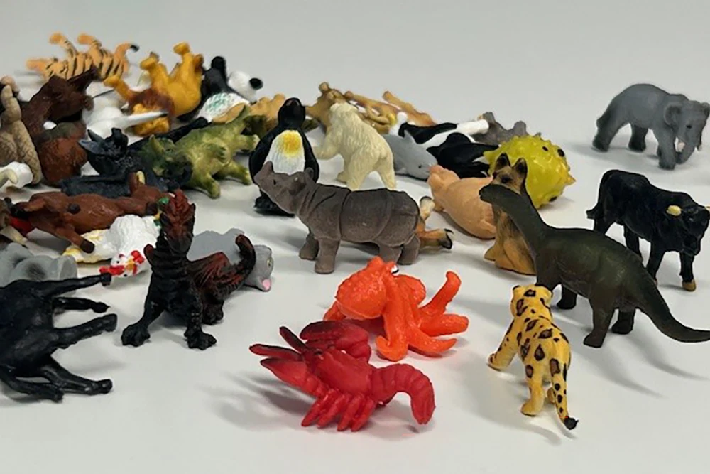 Viele bunte Plastik-Tierfiguren versammelt auf weißem Hintergrund.