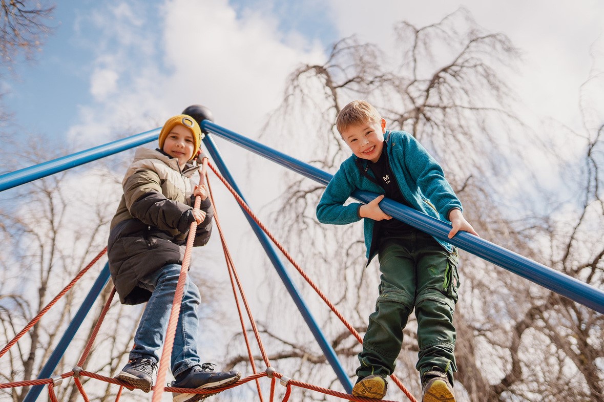Zwei Kinder klettern auf einem Seilgerüst im Park.